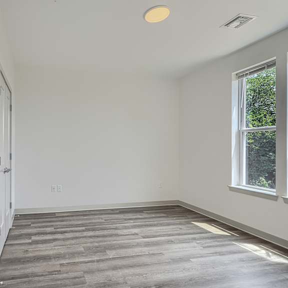 a room with a wooden floor and a window on the right side.