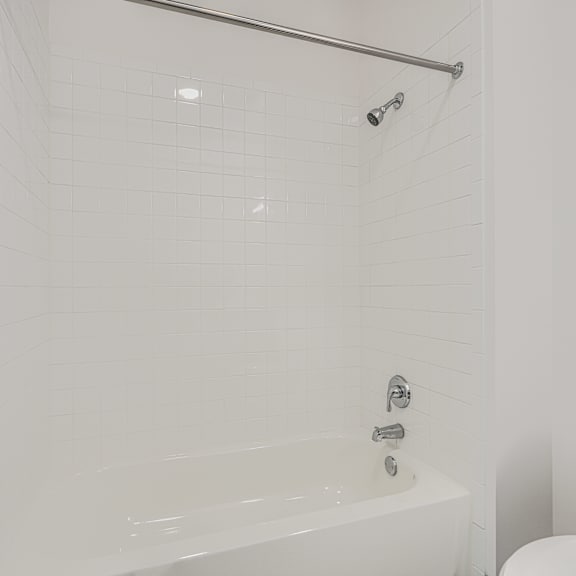 a white bathroom with a tub and toilet.