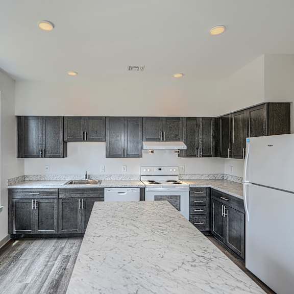 a kitchen with black cabinets and a white refrigerator.