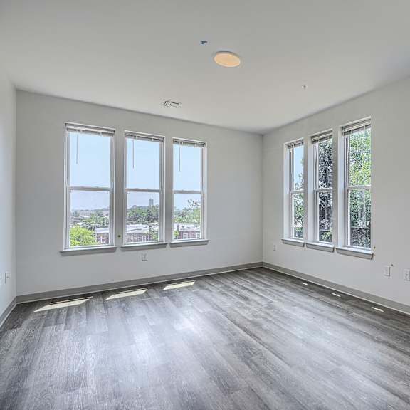 a large empty room with wooden floors and windows.