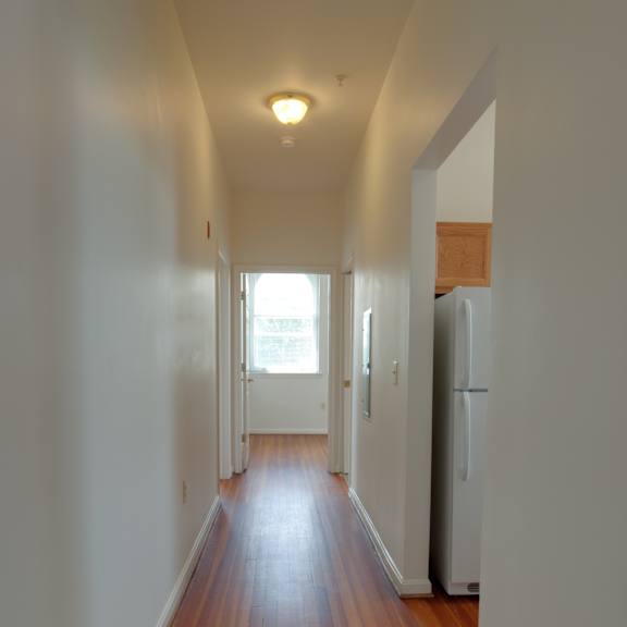 a long hallway with wood floors and white walls.