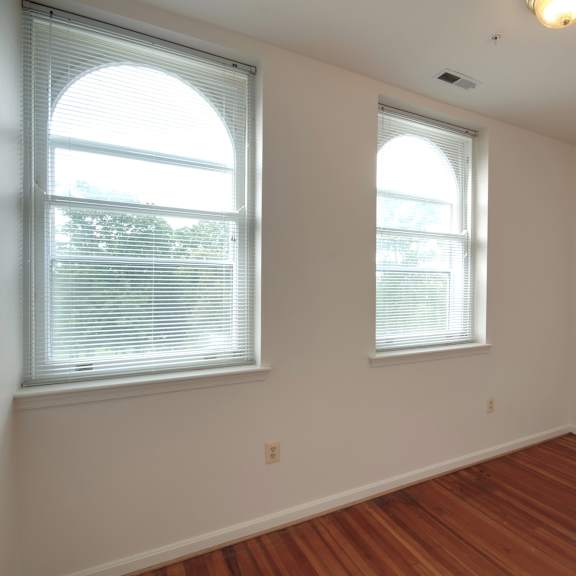 a room with two windows and wooden floors.