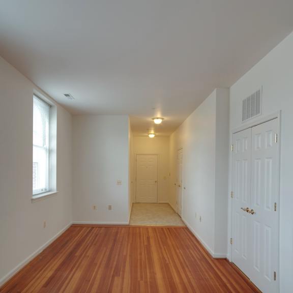 a long, empty hallway with wooden floors and white walls.