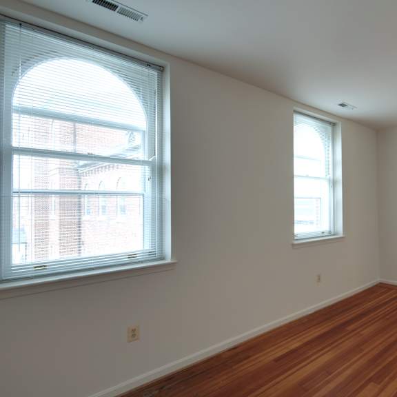 a room with wooden floors and two windows.