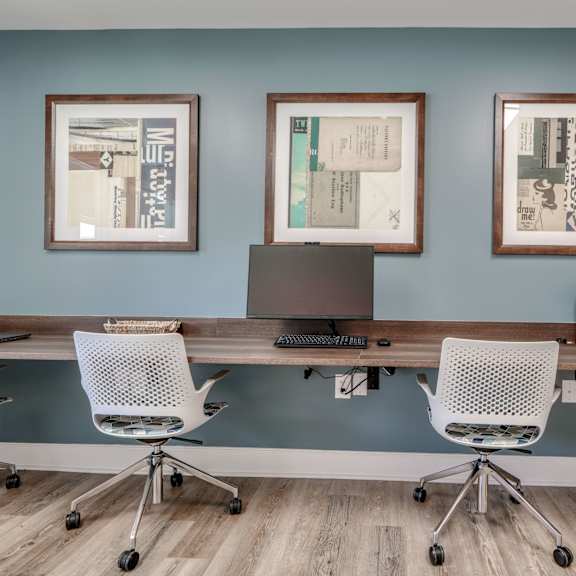 a home office with a desk and three pictures on the wall