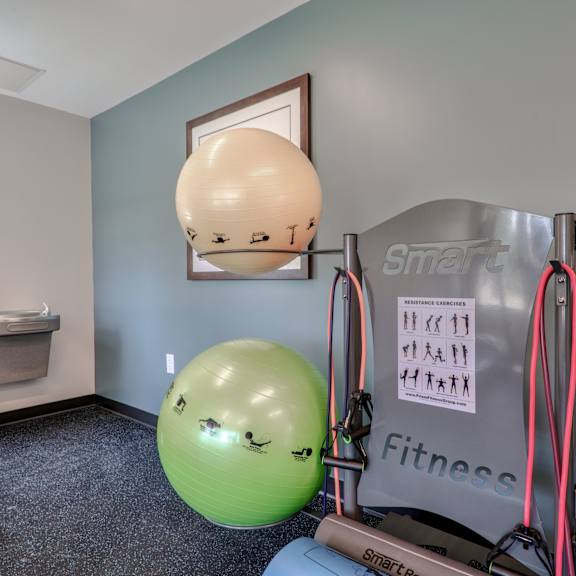 a gym with weights and a ball on the floor and a wall with a picture