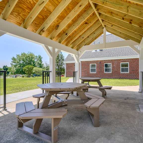 a covered outdoor patio with picnic tables