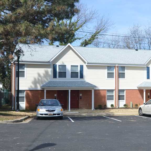 a house with a parking lot and two cars in front of it