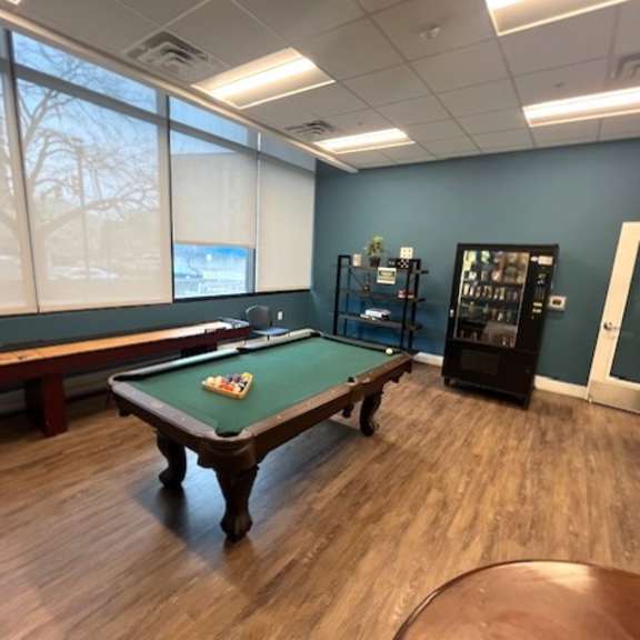 a pool table in a room with a window and a vending machine.