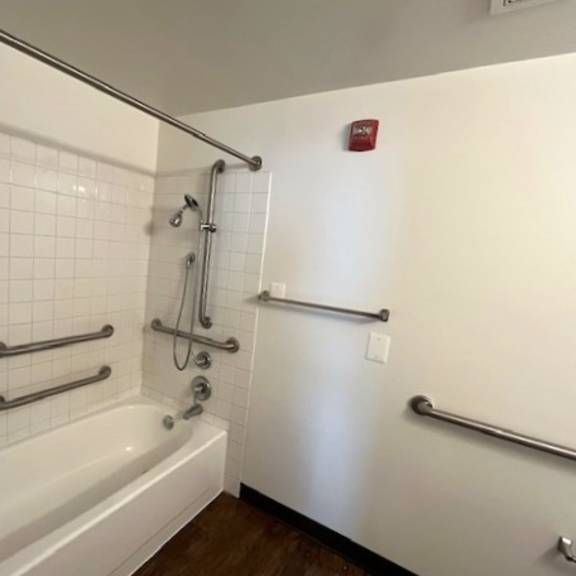 a white tiled bathroom with a white bathtub and a white refrigerator.