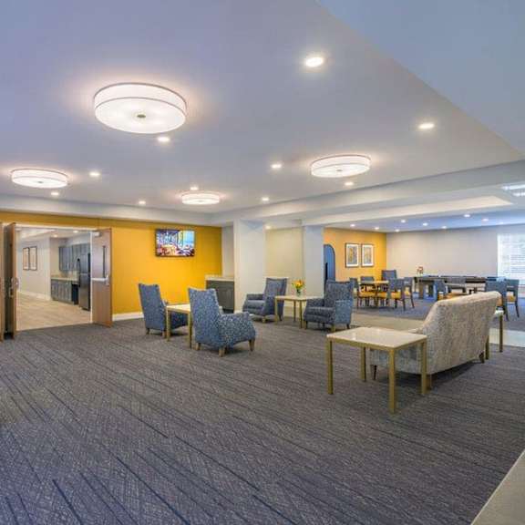 a spacious waiting area with blue patterned chairs and a television.