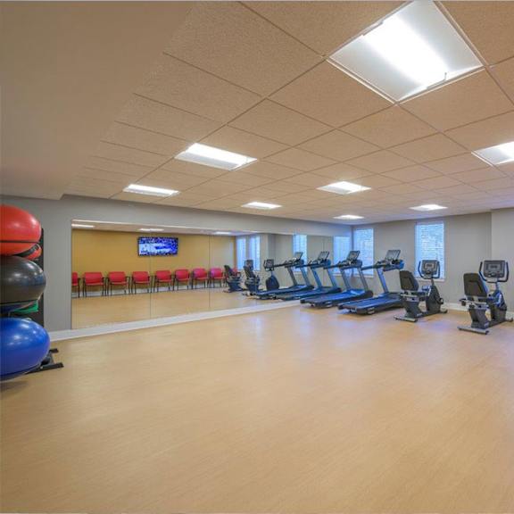 a gym with exercise equipment and red chairs.