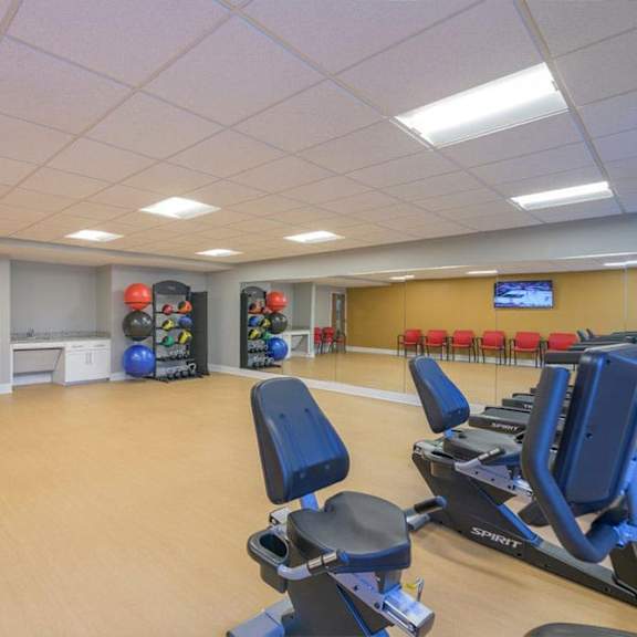 a gym with exercise equipment and a wall of windows.