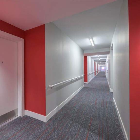 a hallway with a carpeted floor and a door on the left.