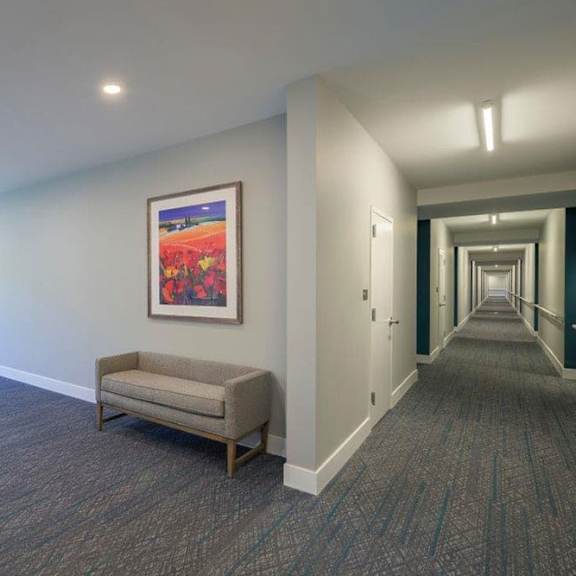 a hallway with a bench and a painting on the wall.