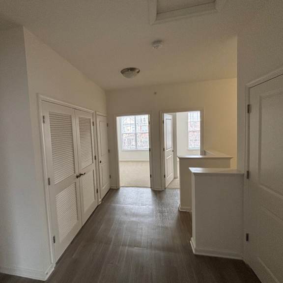 a long hallway with white walls and wood floors.
