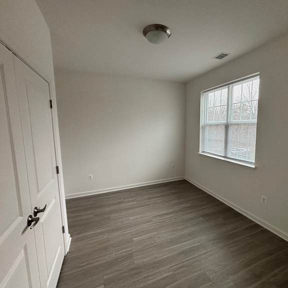 a room with a wooden floor and a window with blinds.