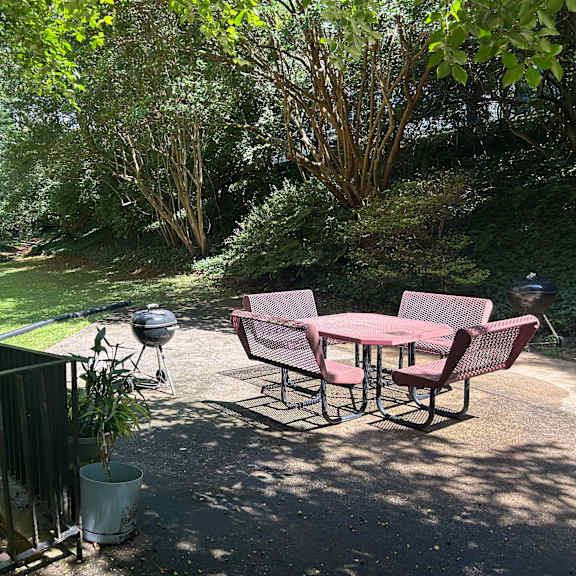 a patio with a table and chairs and a grill.