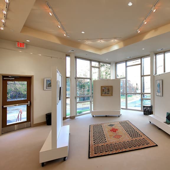 a room with a rug on the floor and a few paintings on the wall.