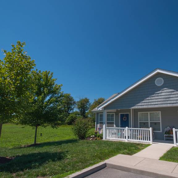 a house with a white fence and a tree in front of it.