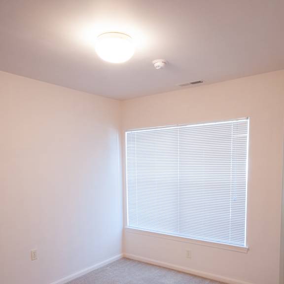 a room with a window covered in blinds and carpet on the floor.