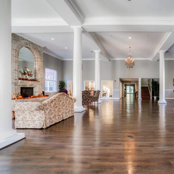 a large living room with white pillars and a fireplace