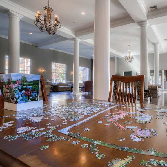 a dining room with a large table covered in jigsaw puzzle pieces