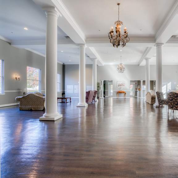 a large living room with columns and a chandelier