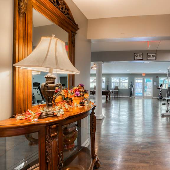 the lobby of a gym with a table with a lamp and a mirror