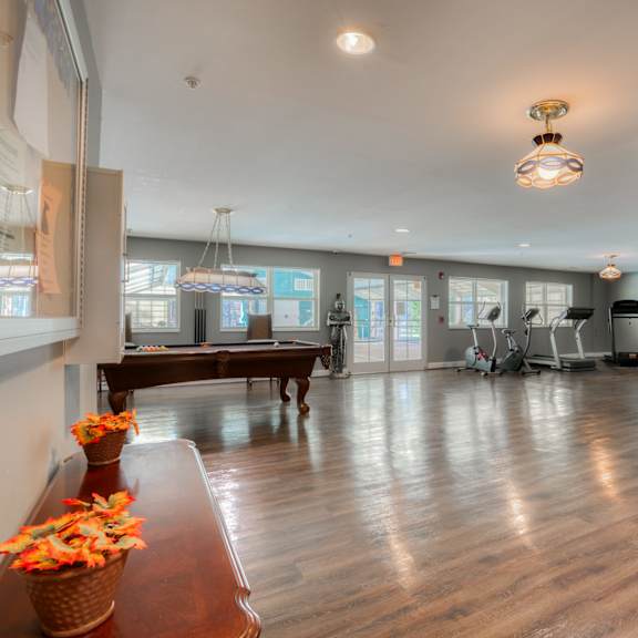 a gym with a pool table and exercise equipment in the corner