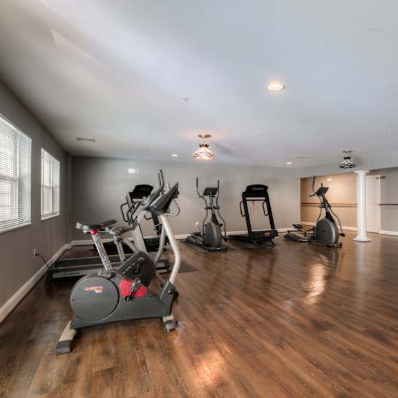 a gym with treadmills and other exercise equipment on a wood floor