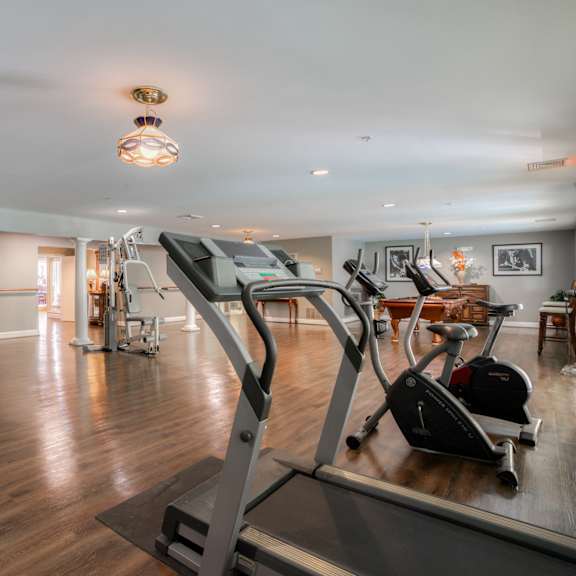 a gym with treadmills and other exercise equipment in a room with wood floors