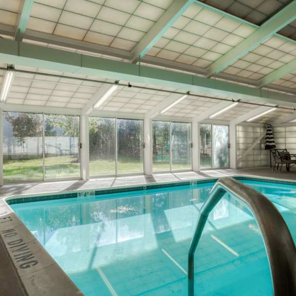 a swimming pool in a room with glass doors and a window