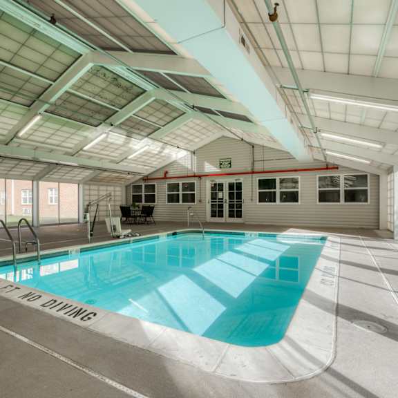 a swimming pool in a building with glass walls and a ceiling