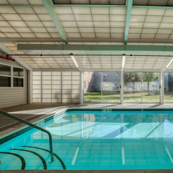 a swimming pool in a room with large windows