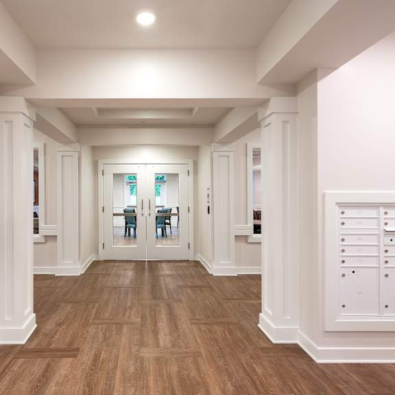a long hallway with white cabinets and white walls and wood floors