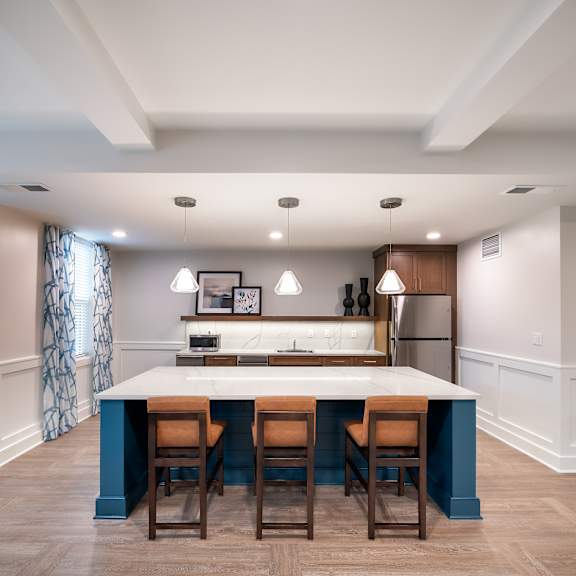 a kitchen with a blue island and wooden chairs
