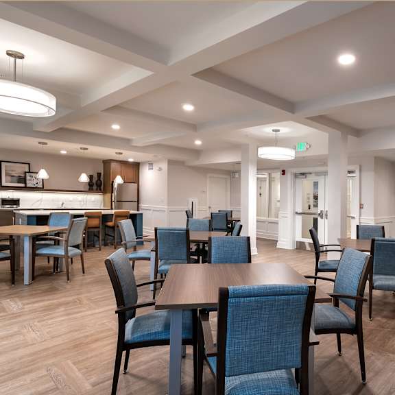 a community room with tables and chairs and a kitchen