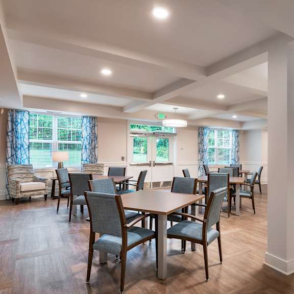 a community room with tables and chairs and a kitchen
