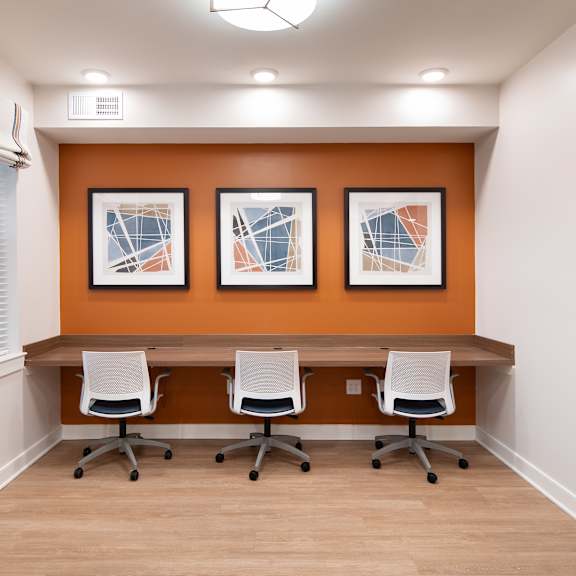 a conference room with four chairs and a desk with three pictures on the wall