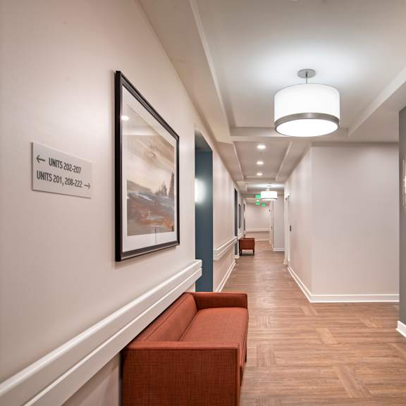 a long hallway with a bench and a painting on the wall and a door