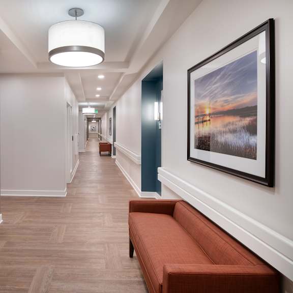 a long hallway with a bench and a painting on the wall