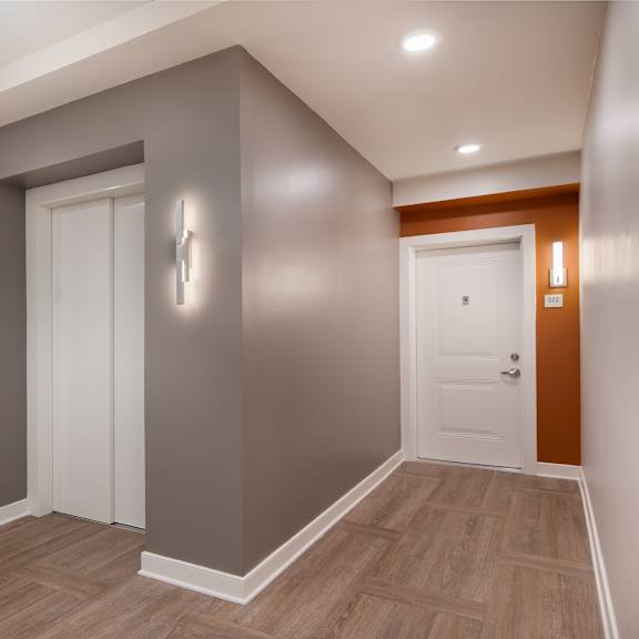 a corridor with a white door and grey walls and a wooden floor