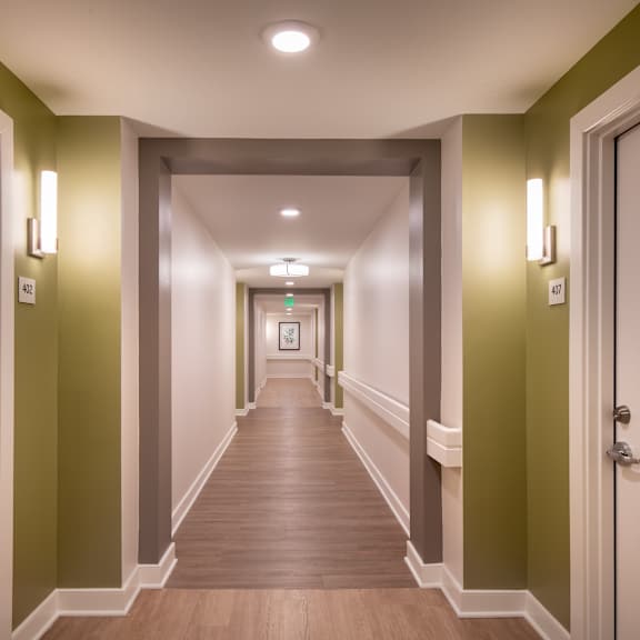 a hallway with green walls and wooden floors and white doors