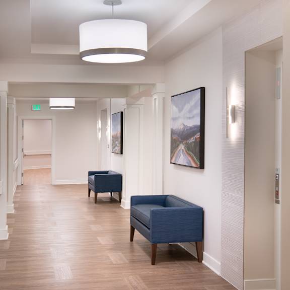 a hallway with blue chairs and white walls and a wood floor