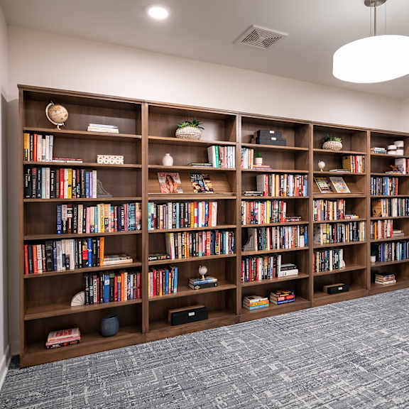 room with bookshelves and a couch in front of a window