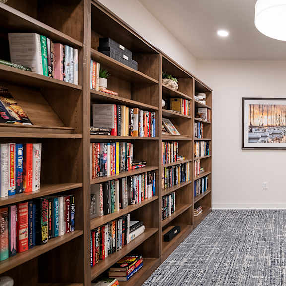 room with chairs and bookshelves and a table with a lamp