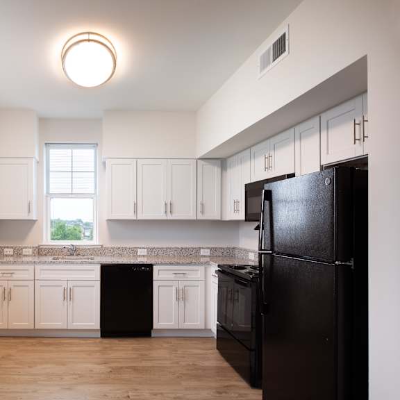 a kitchen with white cabinets and a black refrigerator