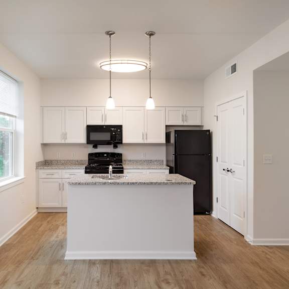 a kitchen with white cabinets and a white island with a black refrigerator