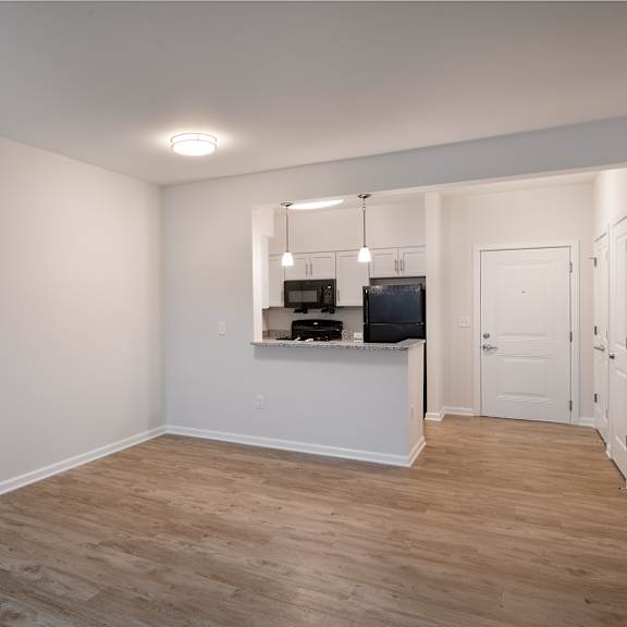 a living room and kitchen with a wood floor and white walls